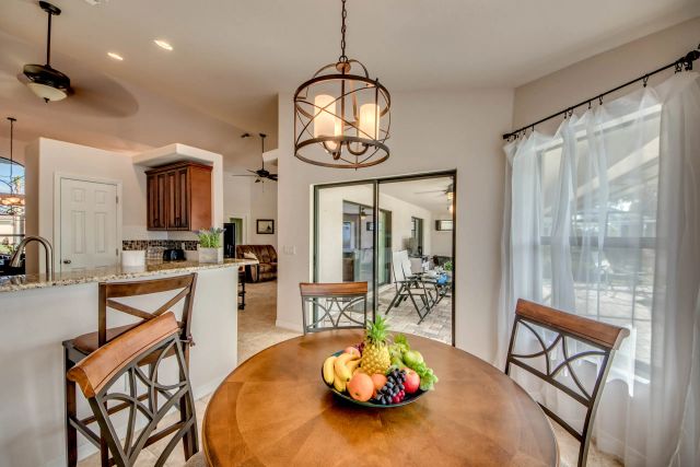 Round wooden table with a bowl of fruit and bar stools, the kitchen behind