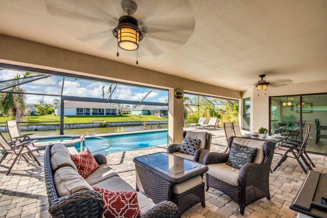 Seating area with sofa and armchairs on the covered lanai, the pool beyond