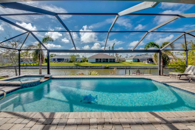 Pool under a blue sky, a lounger on the right, canal and far bank behind