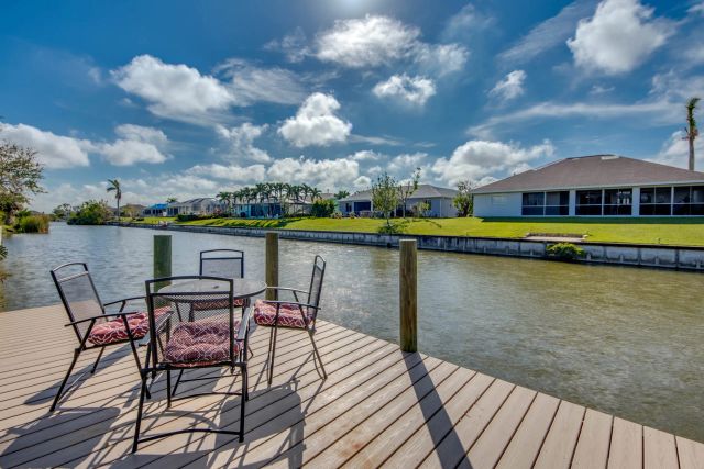 Dock with a table and four chairs on the canal, a house on the far bank