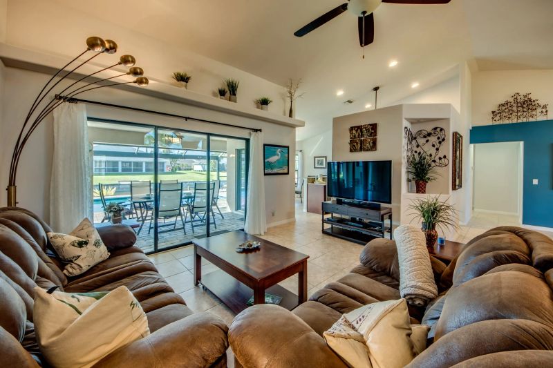 Living area with a brown sofa, TV and glass sliding doors to the lanai