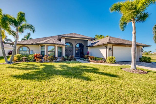 House with arched windows behind a lawn with palm trees