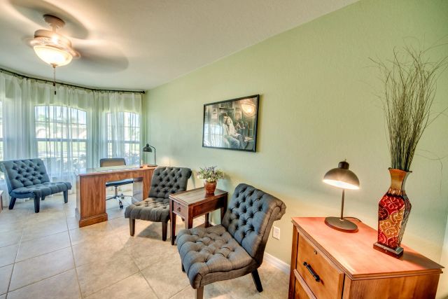 Room with a desk, two upholstered armchairs and a dresser with a vase