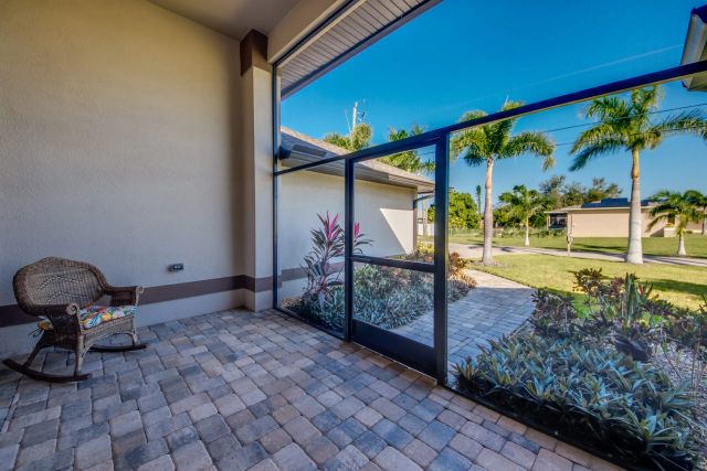 Paved porch with a rocking chair, the garden visible through the screen