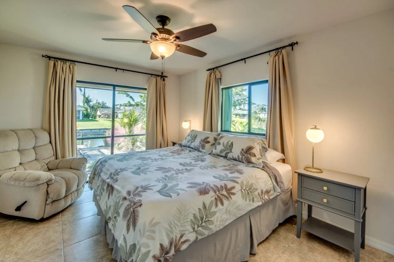 Bedroom with a bed, recliner, nightstand and windows onto the garden