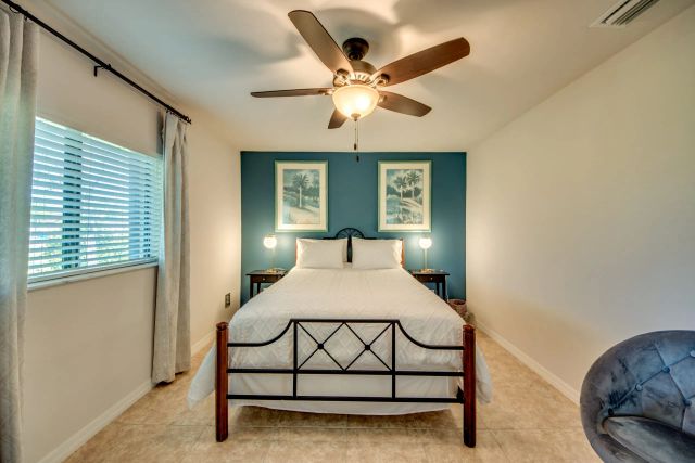 Bedroom with a metal-frame bed against a blue accent wall and a ceiling fan