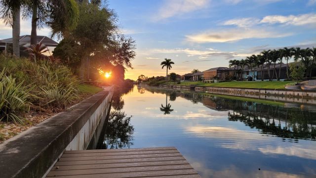 Low sun over the canal reflected in the water, the dock in the foreground