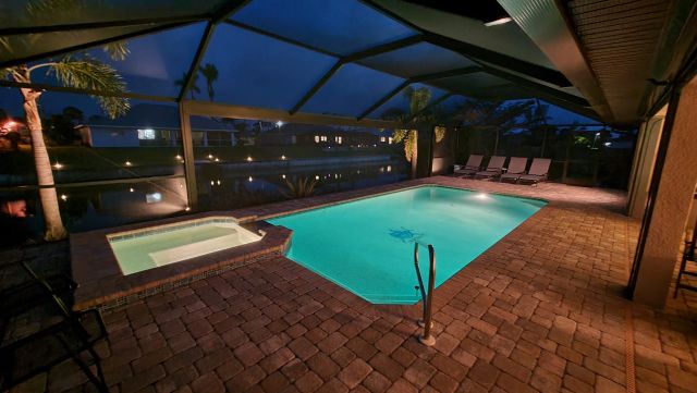 Illuminated pool and spa at night inside the screen enclosure