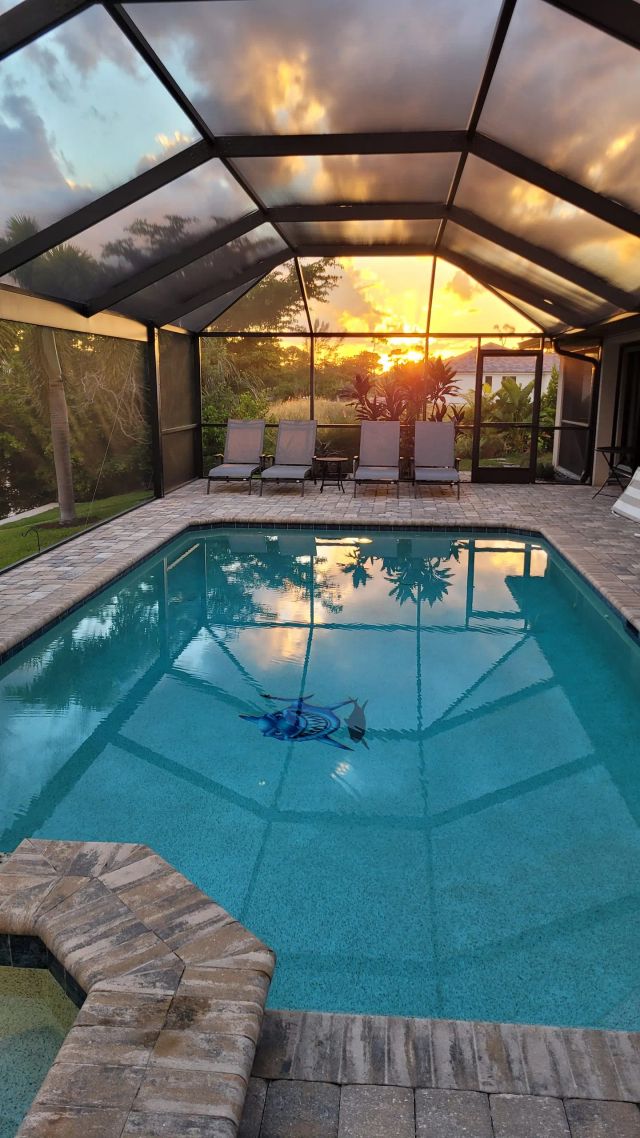 Pool inside the screen enclosure with an orange sky behind